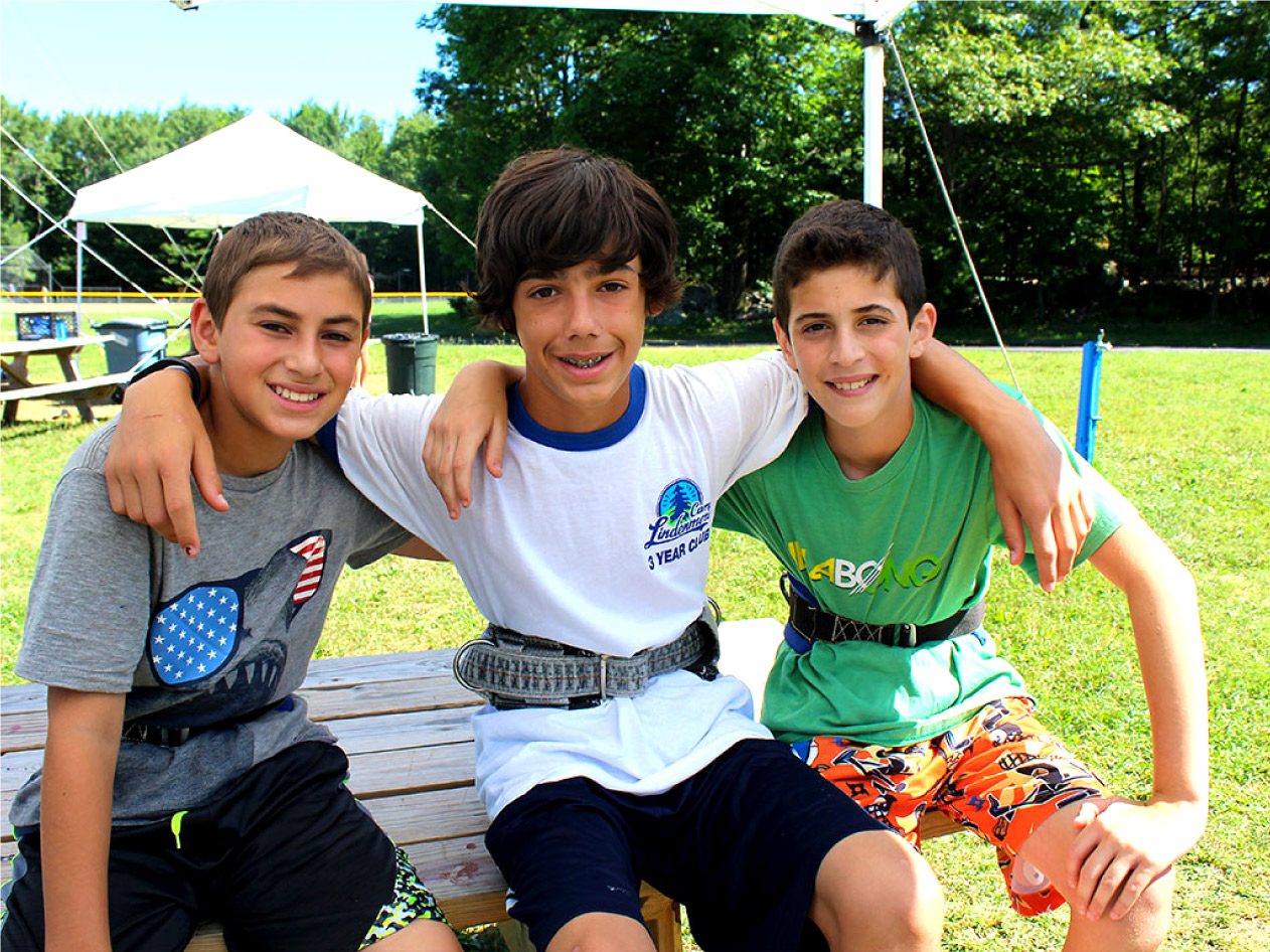 Three male campers by flying trapeze smiling