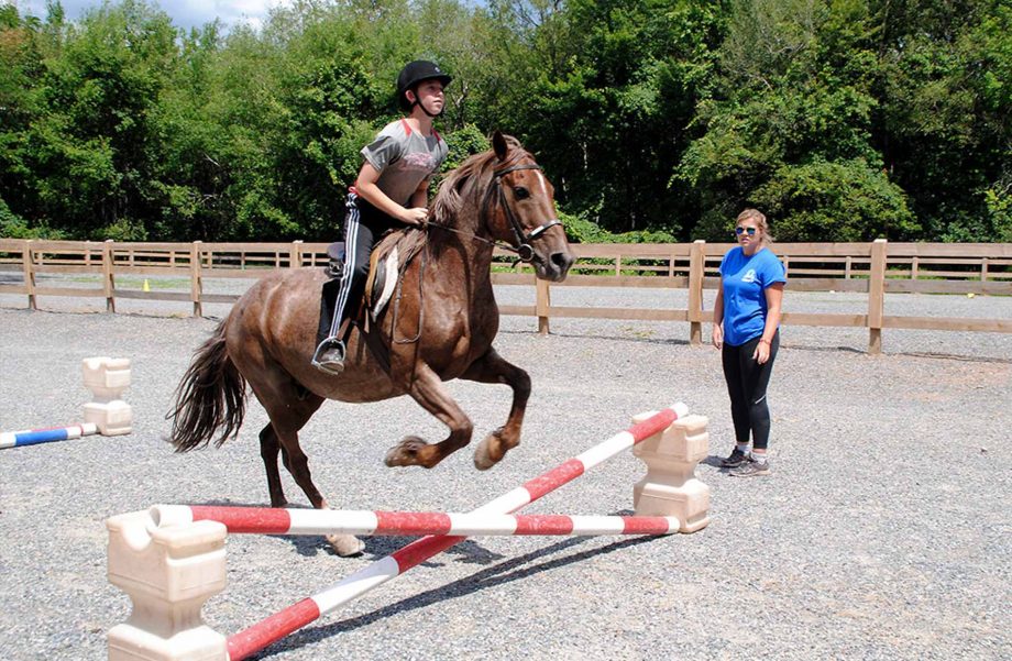 Camper and horse jumping over obstacle