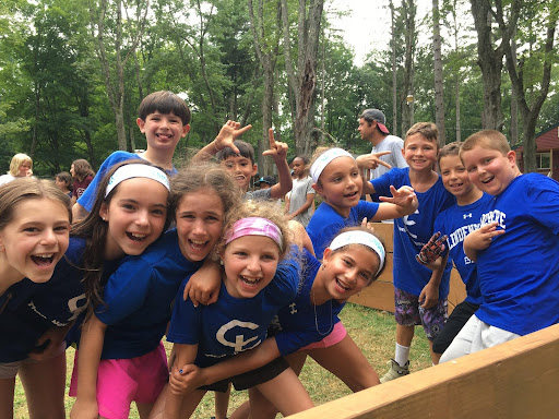 A group of kids in blue shirts smiling in a Gaga court.